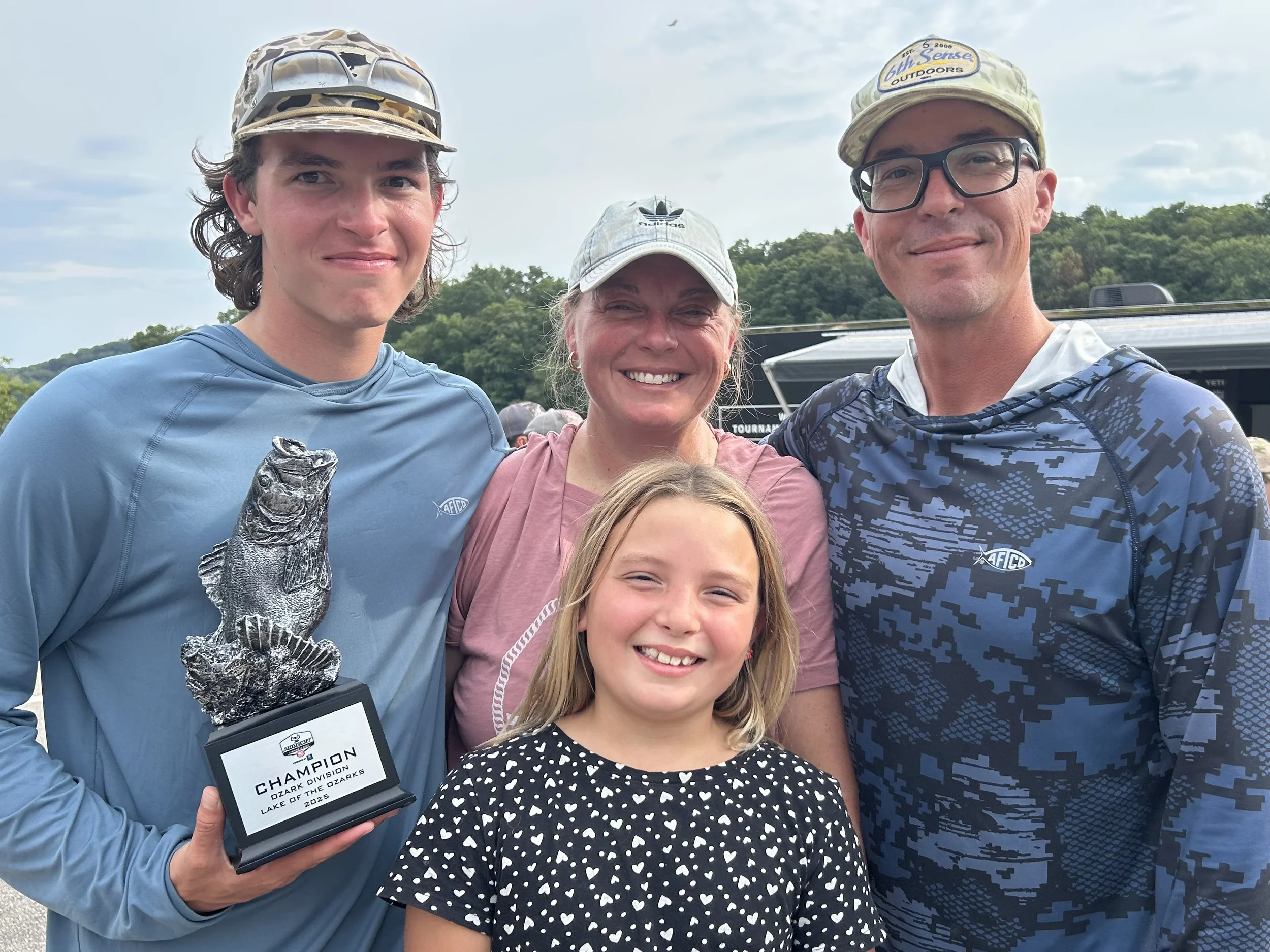 family smiling and posing with trophy
