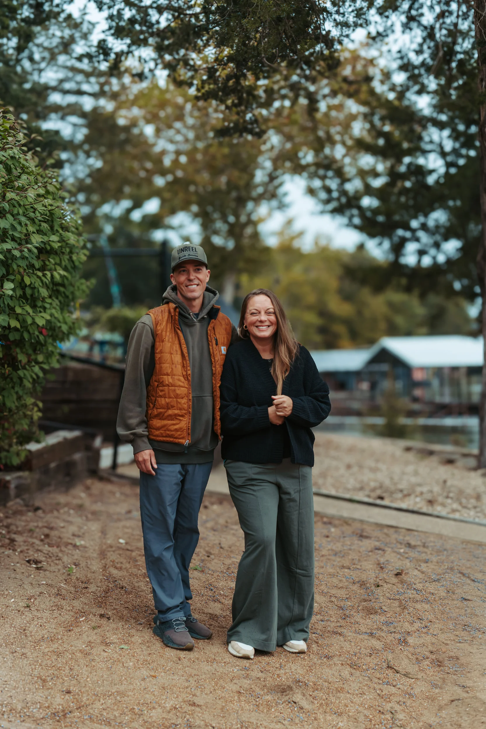 husband and wife smiling for the camera standing by the water